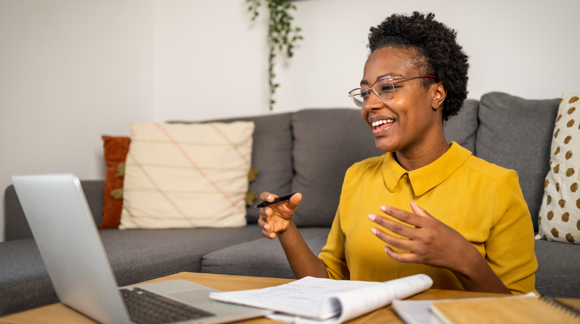 A young black woman engaged in virtual learning on a couch with a laptop.